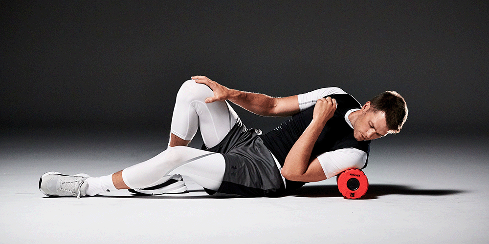 Tom Brady rolling out his shoulder and upper back with a red foam roller